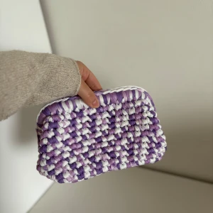 Necessär  - Superfin handgjord necessär i lila och vitt med chunky, flätad design. Perfekt för dig som vill sticka ut med en unik accessoar! Väskan har en mjuk, fluffig känsla och passar till alla tillfällen när du vill addera lite färg. Kolla gärna in vår Instagram @design.by.bela för fler necessärer och väskor. 