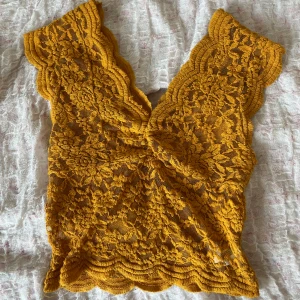 Gul spetsblus från Zara - Säljer en gul trendig topp från Zara i vacker spets med djup v-ringning och fina volangdetaljer längs ärmar och nederkant. Perfekt för dig som vill ha något färgstarkt och unikt i garderoben!