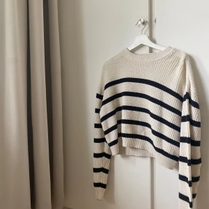 Randig stickad croppad tröja - Säljer en beige stickad tröja med svarta horisontella ränder. Tröjan är croppad och har lång ärm samt rund halsringning. Perfekt för dig som gillar en avslappnad men trendig stil. Pris diskuteras💘
