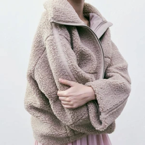 Beige teddyjacka med dragkedja - Mysig och trendig beige teddyjacka med hög krage och grov dragkedja. Perfekt för kyliga dagar när du vill vara både varm och snygg.