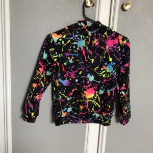 Färgglad hoodie med stänkmönster från SHEIN - Cool hoodie från SHEIN i svart med färgglatt stänkmönster i neonfärger. Tröjan har långa ärmar och huva, perfekt för dig som vill sticka ut. Mjuk och bekväm, passar till många tillfällen.