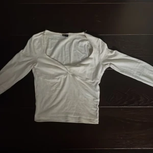 Vit långärmad topp från Gina Tricot - Säljer en stilren vit långärmad topp från Gina Tricot. Toppen har en v-ringad design och är tillverkad i ett mjukt material som ger en bekväm passform. Perfekt för att matcha med olika outfits. 