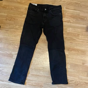 Svarta jeansbyxor från H&M - Snygga svarta jeansbyxor från H&M med straight passform. De har en klassisk design med fyra fickor och knappar i midjan. Perfekta för en stilren look.