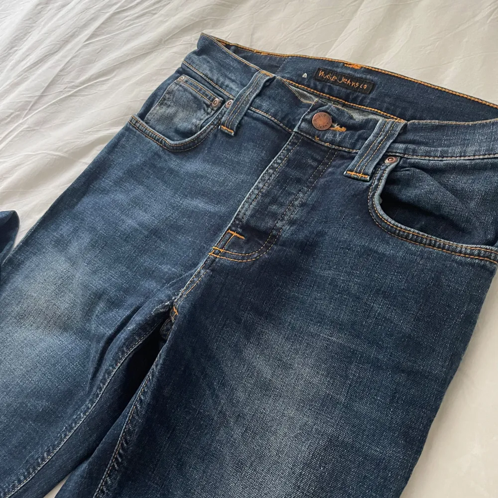 Snygga mörkblå jeans från Nudie Jeans i slim med en klassisk femficksdesign. De har en knappgylf och subtila slitningar för en trendig look. Perfekta för dig som gillar en stilren och tidlös stil.. Farkut & Housut.