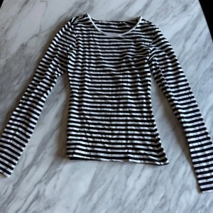 Svartvit randig långärmad topp - Säljer en stilren svartvit randig topp med långa ärmar. 