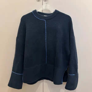 Mörkblå stickad tröja med blå detaljer - Säljer en super snygg mörkblå stickad tröja med kontrasterande ljusblå sömmar. 