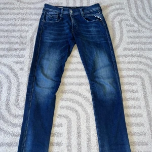 Replay jeans - Snygga blå jeans från Replay i modellen Anbass. Jeansen har en tvättad look med subtila slitningar. Storlek: W29. Passar mig bra som är ca 175 o 62kg👌Kontakta vid andra frågor🤩