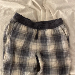 Pyjamasbyxor  - Säljer ett par bekväma mjukisbyxor med rutigt mönster i grått/blått och vitt. Byxorna har en elastisk midja och är i storlek 158/164. Dom är i fint skick. PRIS KAN DISKUTERAS 