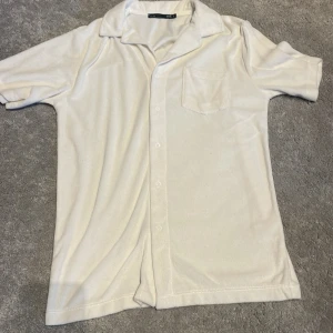 Vit kortärmad skjorta från 157 - Säljer en stilren vit kortärmad skjorta från 157. Skjortan har en klassisk krage och knappar framtill samt en bröstficka. Perfekt för varma dagar!