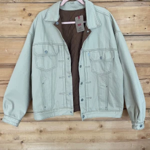 Beige och brun vändbar jacka från Levi's - Säljer en vändbar jacka från Levi's i beige och brun med quiltad insida. Ena sidan är beige med bröstfickor och knappar, medan den andra är brun med svarta quiltade ärmar och fickor. Perfekt för att variera stilen! 🧥