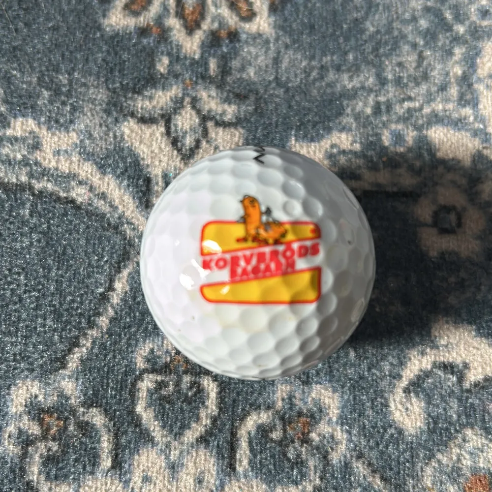 Säljer en vit golfboll från Maxfli med en unik korvbröds logga. Bollen har texten 'TOUR FIRE' och siffran 7 tryckt på sig. Perfekt för golfentusiaster som vill ha något annorlunda på banan! 🏌️♂️. Muu.
