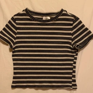Randig ribbad topp - Säljer en snygg randig topp från Divided. Den är ribbad och har korta ärmar med en tight passform. Perfekt för en casual look! Köparen står för frakten + använder köp nu!