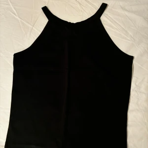 Ny svart linnetopp från Gina Tricot - En stilren svart linnetopp från Gina Tricot i storlek XS. Toppen har raka linjer, smala axelband och hög halsringning. Ej använt.