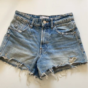 Blå jeansshorts - Snygga blå jeansshorts från Zara med fransiga kanter och slitna detaljer både fram och bak. Materialet är robust denim som håller formen.