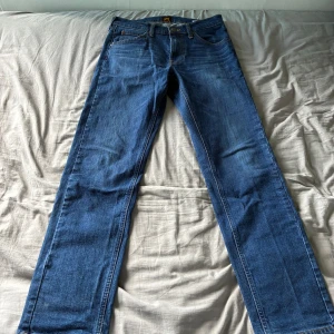 Blå Lee Daren jeans W29 L32 - Säljer ett par klassiska blå Lee Daren jeans med zip-fly. De har raka ben, fem fickor och snygga kontrastsömmar. Jeansen är i bomull och har en normal passform. Perfekta för dig som gillar en tidlös look.