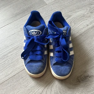 Blå Adidas Campus sneakers mocka - Snygga blå Adidas Campus sneakers i mocka med klassiska vita ränder på sidorna! Knappt använda, endast fåtal gånger!! 