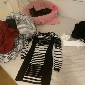 Svartvit randig långärmad klänning - Snygg svart och vit klänning med långa ärmar och coolt randigt mönster. Figurnära passform och knälång modell, perfekt för dig som gillar en stilren look med edge. Mjuk och stretchig, passar både till sneakers och boots.