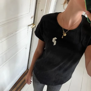 Svart t-shirt Peak Performance S ( aldrig använd) - Svart t-shirt från Peak Performance i bomull med vit logga framtill och större logga på ryggen. Klassisk rund hals och korta ärmar, perfekt till jeans eller shorts. Enkel och stilren design som funkar året runt.