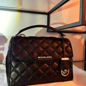 Svart quiltad handväska Michael Kors ”Äkta lammskinn” - Snygg svart quiltad handväska från Michael Kors i äkta lammskinn med silverfärgade detaljer och MK-logga. Väskan har både handtag och axelrem, samt praktiskt innerfack med dragkedja. Perfekt för dig som vill ha en stilren och lyxig accessoar. Sparsamt använt. Välvårdat. Köpt från Zalando, ord pris 3999kr