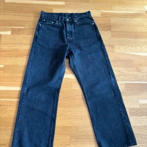 Svarta Criss Jeans från HOPE, stl 32 - Säljer ett par svarta Criss Jeans från HOPE i rak modell. Jeansen har klassisk femficksdesign, hög midja och raka ben. Tillverkade i kraftig denim med HOPE-logga bak i linningen. Perfekta för dig som gillar stilrena och tidlösa jeans.