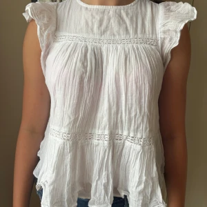 Vit blus med volang - Supersöt vit blus från Gina Tricot med volangärmar och fina spetsdetaljer. Blusen är stor i storleken, skulle säga att den känns som XS! Säljer på grund av att den inte kommer till användning. Pris kan diskuteras!💖