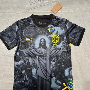 Nike Brasil fotbollströja - Snygg svart Brasilien fotbollströja från Nike med unikt grafiskt tryck av Kristusstatyn och brasilianska motiv på framsidan. Tröjan har korta ärmar, rund hals och är tillverkad i lätt Dri-FIT material som andas. Gula detaljer med Nike-logga och Brasilien-emblem på bröstet.