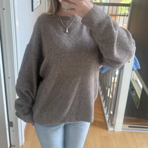 Brun oversized stickad tröja - Mysig brun stickad tröja med oversized passform och långa ärmar. Tröjan har en enkel rund halsringning och ribbade muddar vid ärmslut och nederkant. Perfekt för lager-på-lager och chill dagar.