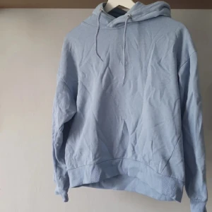 Ljusblå hoodie från 157, XS - Ljusblå hoodie från 157 i mjuk bomull med klassisk huva och snörning. Tröjan har ribbade muddar vid ärmslut och nederkant samt en relaxed passform. Perfekt för chill dagar eller när du vill ha en enkel och stilren look. Kan upplevas något nopprig i visst ljus, därav priset. 