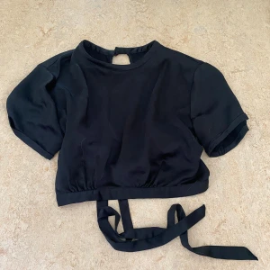 Svart topp - Snygg svart omlottopp med korta ärmar och knytband i ryggen även en knapp i nacken💕