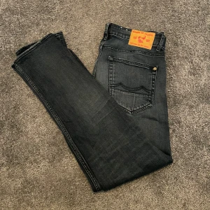 Svarta jeans från Kings of Indigo - Snygga svarta jeans från Kings of Indigo med klassisk femficksdesign och subtila slitningar. Jeansen har raka ben och normal passform. Hör av er vid funderingar