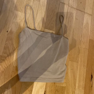 Beige linnetopp från Gina Tricot - Säljer en stilren beige linnetopp från Gina Tricot med tunna axelband. Toppen är enkel och passar perfekt till jeans eller kjol. Mjuk och skön bomullskänsla, perfekt för varma dagar eller lager på lager.