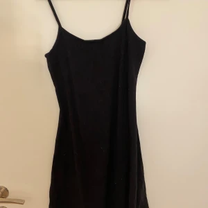 Svart kort klänning  - Enkel svart kort klänning från H&M Divided med smala axelband och fin passform. Tyget ger en mjuk bomullskänsla