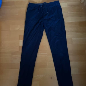 Mörkblå linnebyxor från H&M med snörning - Snygga mörkblå linnebyxor från H&M med avslappnad passform och dragsko i midjan. Perfekta för en chill och stilren look. Byxorna har raka ben och är tillverkade i ett lätt och luftigt linnematerial.