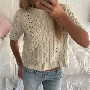 Beige kabelstickad tröja från Zara - Superfin beige kabelstickad tröja från Zara med trekvartsärmar. Tröjan har ett snyggt flätmönster och ribbade kanter som ger en chill och trendig vibe. Perfekt att styla med jeans eller kjol för en avslappnad look. Känns inte som en L, mer som   S-M