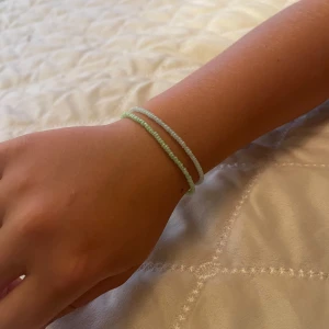 Två tunna pärlarmband i pastell - Säljer två supertunna armband med små pärlor i pastellfärger, ett i ljusgrönt och ett i ljusblått. Perfekta att mixa och matcha med andra smycken för en enkel och fräsch look. Stretchiga och lätta att ta på.