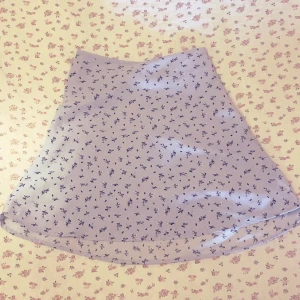 Blå blommig kjol - Supersöt ljusblå kjol med små blommor på. Kjolen stängs med en dragkedja i sidan. Perfekt för dig som gillar en romantisk och feminin stil.