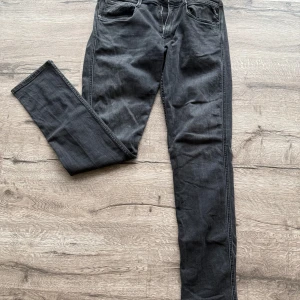 Replay Anbass - Snygga svarta Replay Anbass jeans i slim fit med klassisk femficksdesign. Jeansen har en mörk tvätt och diskreta slitningar, tillverkade i mjukt denimtyg. Perfekta för dig som gillar en smalare passform och stilren look. Skick 10/10. Skicka pm vid minsta fundering