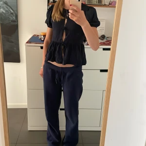 Mörkblå blus från Gina Tricot - Säljer en mörkblå blus från Gina Tricot i storlek 158/164. Den har tre rosetter längs tröjan och passar perfekt för en gullig look.