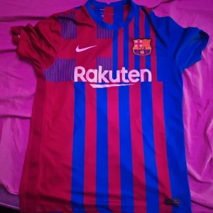 FC Barcelona  - Säljer en FC Barcelona matchtröja från Nike i storlek M men passar mycket s jag har s oxh den är slim fit. Tröjan har klassiska blå och röda vertikala ränder, klubbmärke på bröstet, Rakuten-tryck fram och Unicef-tryck bak. Tillverkad i Dri-FIT-material som andas, perfekt för fotboll eller träning.