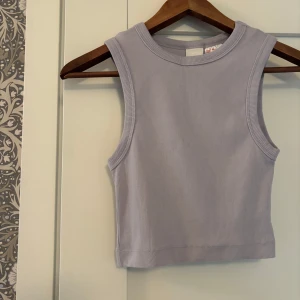 Ljuslilagrå ribbad linnetopp - Superfin ljuslilagrå ribbad linnetopp från H&M. Croppad modell med breda axelband och rund halsringning. Perfekt att styla med jeans eller kjol för en chill look. Mjuk och stretchig bomullskänsla som sitter snyggt på kroppen.