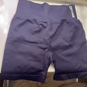 Mörkblå träningstights-shorts från DFYNE - Snygga mörkblå träningstights-shorts från DFYNE med hög midja och ribbad linning. Shortsen har en tight passform och scrunch-detalj bak för extra shaping. Perfekta för gymmet eller andra träningspass. Använd fåtal gånger.