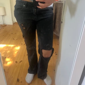 Svarta slitna jeans med hål - Svarta jeans med coola slitningar och hål på benen. . Lågmidjade och bootcut