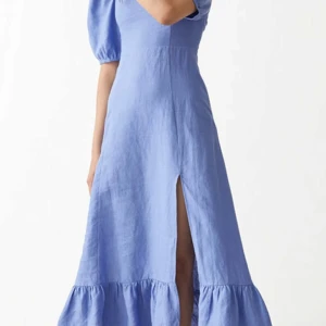 Ljusblå långklänning från & Other Stories  - Superfin ljusblå långklänning från & Other Stories, med puffiga kortärmar och fyrkantig ringning. Klänningen har en slits framtill och volang nertill.  Använd 1 gång sedan tvättad. Nypris 999kr.