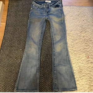 Blå bootcut jeans från Filippa K - Snygga blå bootcut jeans från Filippa K med klassisk femficksmodell och ljusa slitningar. Jeansen har låg midja och är tillverkade i mjukt denimtyg som ger en avslappnad vibe. Perfekta för dig som gillar retrostil och vill ha ett par jeans med lite extra attityd.