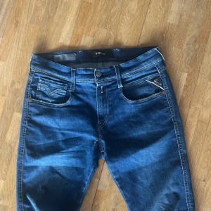 Blå Replay jeans - 28/32 - dem har slitits lite mellan benen men är väldigt lätt och fixa om man orkar därför jag säljer dem.  Storlek: 28-32.      Blå jeans från Replay med klassisk femficksdesign och snygga kontrastsömmar. Jeansen har en normal passform och raka ben, samt läderpatch med Replay-logga bak. Perfekta för dig som gillar stilrena och tidlösa jeans med coola detaljer.