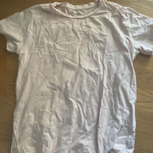 Ljusrosa t-shirt från 157 - En basic ljusrosa t-shirt från 157 i 100% ekologisk bomull. Klassisk rund halsringning och korta ärmar, perfekt för en clean och enkel stil. Passar dig som gillar minimalistiska plagg och mjuka material.