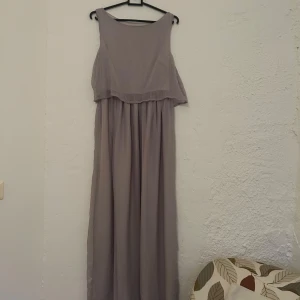 Ljusgrå långklänning med öppen rygg - Säljer en ljusgrå långklänning med öppen rygg. Hittar inge lapp men gissar på att den är i storlek M/L