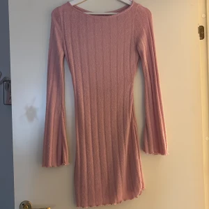 Rosa ribbad klänning Gina Tricot XS - Supersöt rosa kortklänning från Gina Tricot i ribbat material. Klänningen har långärmade trumpetärmar, vågig kant nertill och en snygg öppen rygg. Perfekt för dig som gillar en feminin och trendig look. Den är lite genomskinlig men super bekväm och snygg!! Den är i storlek XS men den är stretchig så den passar även storlek S!!!<3