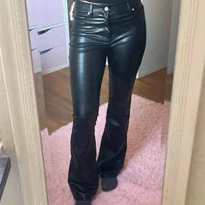 Svarta bootcut byxor i skinnlook H&M - Snygga svarta bootcut byxor från H&M Divided i skinnimitation. Byxorna har hög midja och utsvängd bootcut. Byxorna är tall girl friendly (jag är 1,73) från midja till slut är byxorna 108 cm långa. Jättefina byxor fortfarande i jättefint skick!💗
