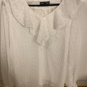 Vit blus - Säljer denna jättefina eleganta blusen. Med en volang. Aldrig använd då den är stor på mig. Lite stor i storlek skulle jag säga.